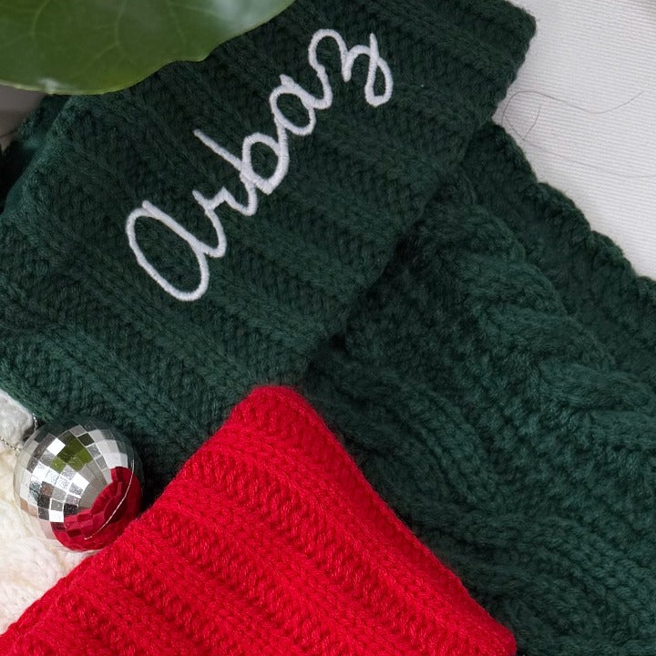 Close-up of a name embroidered on a cable-knit Christmas stocking